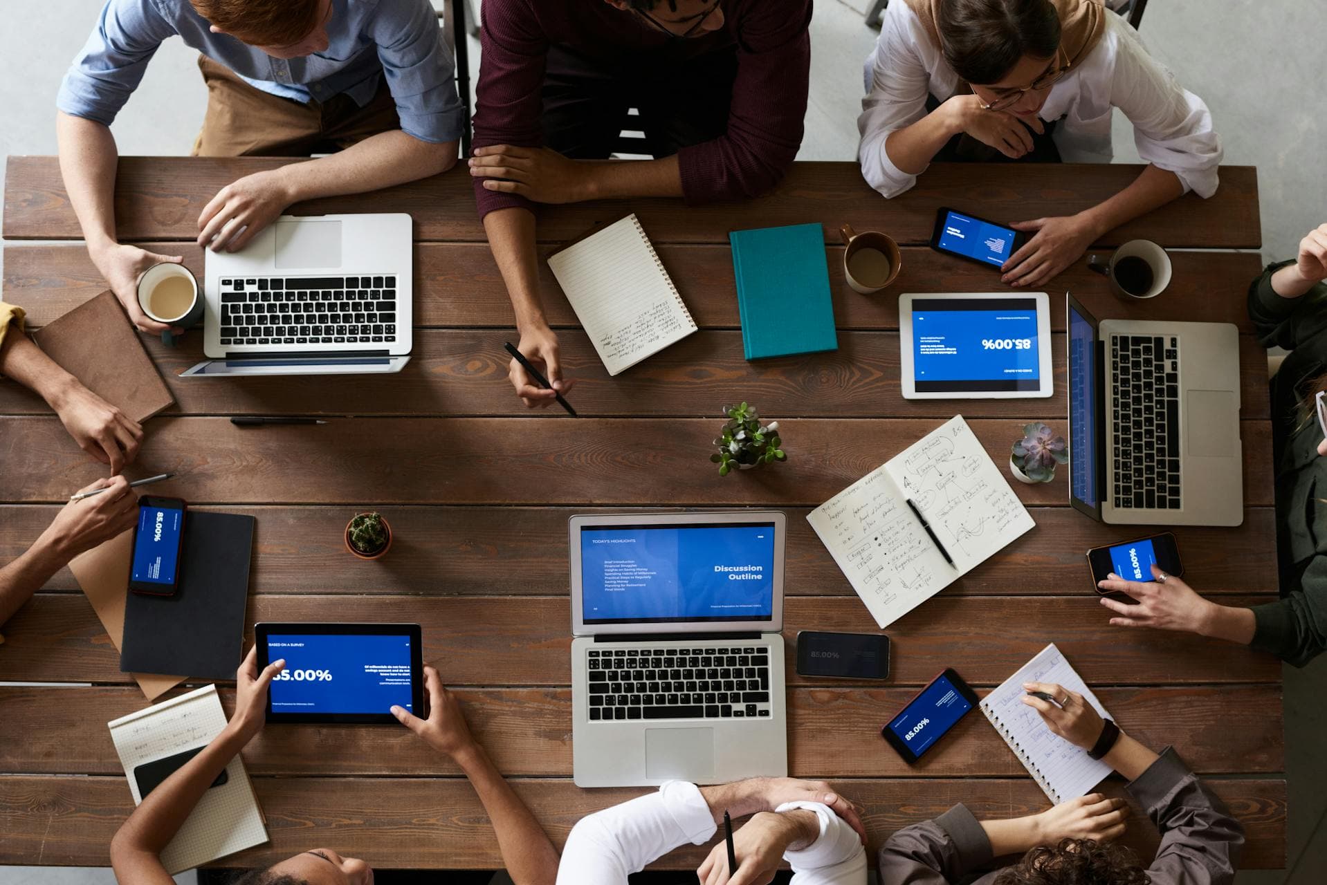 Team collaborating around a table with laptops and tablets during a workshop